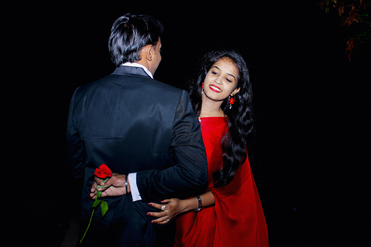 Пара на романтическом свидании, мужчина дарит женщине розу, оба счастливо улыбаются.