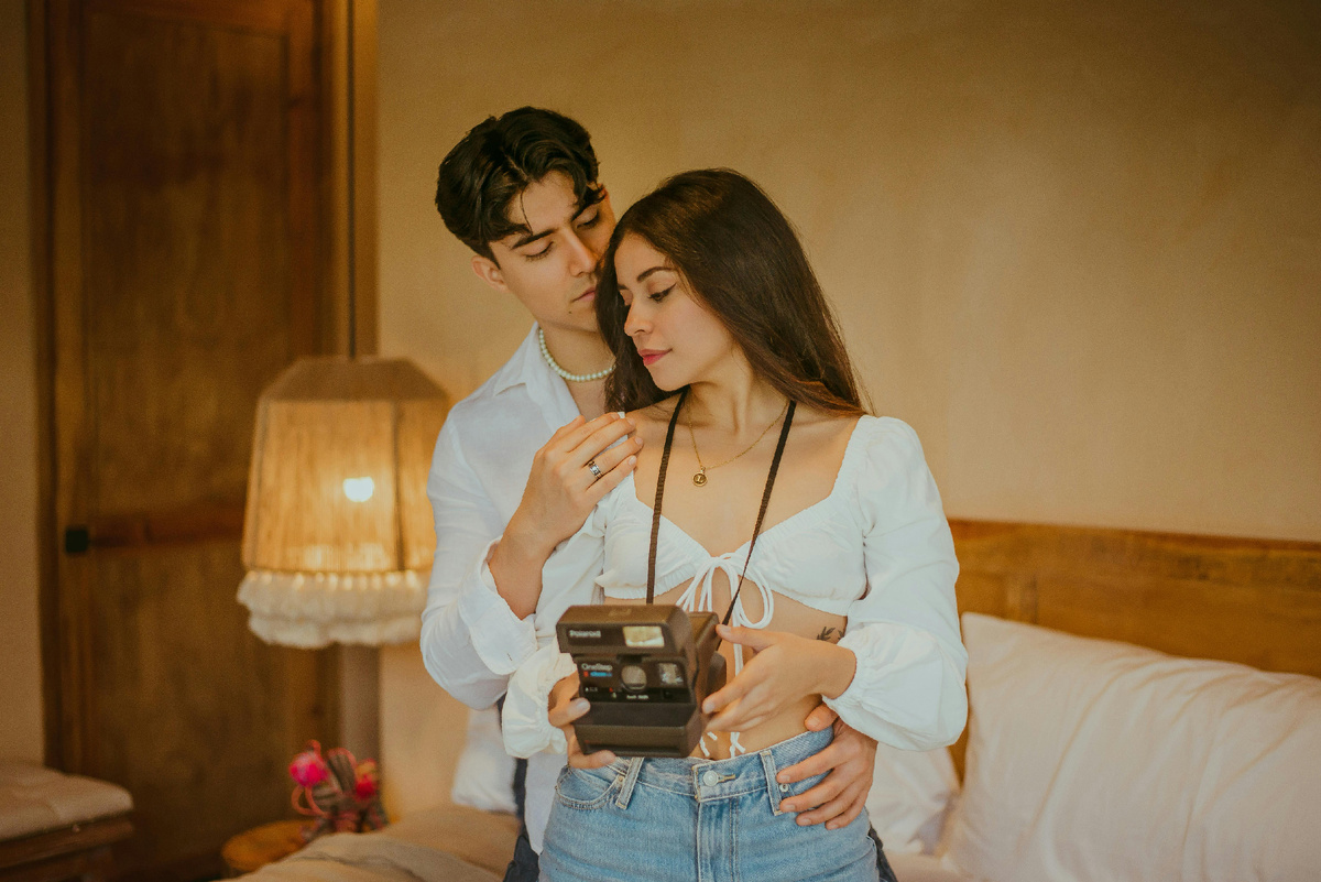 Парень обнимает девушку, стоящую с фотоаппаратом в руках