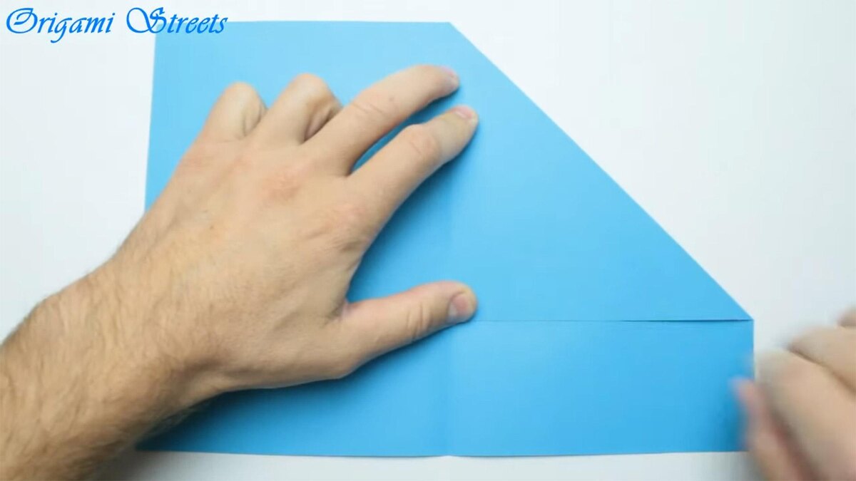    Разверните бумагу и согните левую часть к середине. Пригладьте линию сгибаOrigami Streets / YouTube