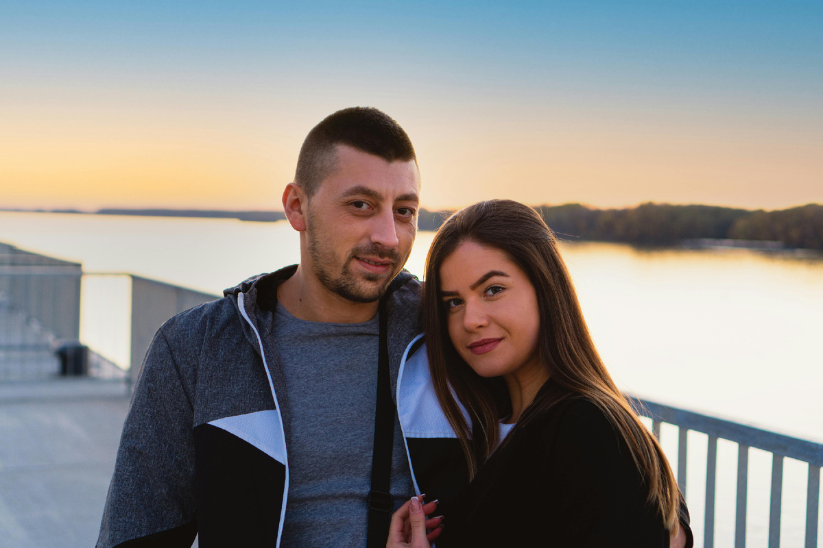 Пара обнимается на набережной на закате, наслаждаясь спокойствием и доверием друг к другу