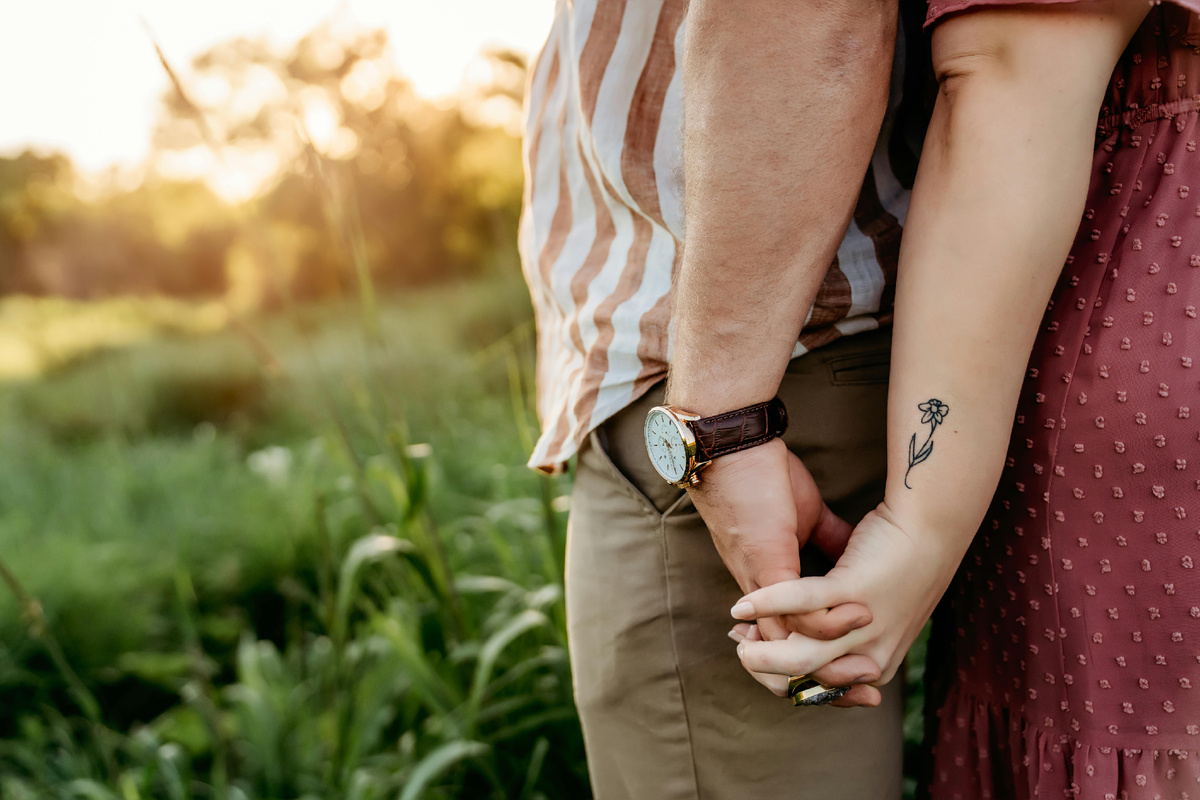 Пара держится за руки на закате, символизируя доверие и поддержку друг друга