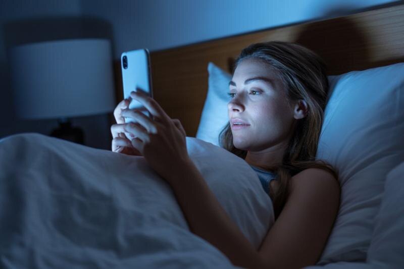    Ideogram. Женщина держит телефон, лежа в постели