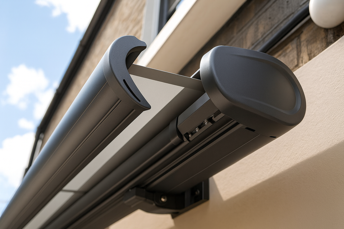 Детальный вид на механизм современной касетной маркизы, установленной на фасаде дома. Видны направляющие, система и крепления. На фоне — голубое небо с облаками. Конструкция выполнена из прочного алюминия, идеально подходит для защиты от солнца и дождя.