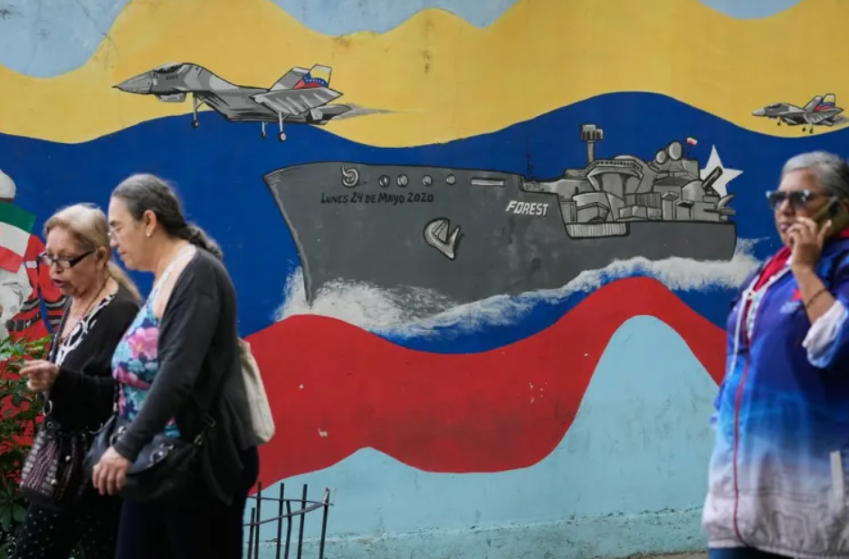 Пешеходы проходят мимо настенной росписи с изображением венесуэльского военного корабля и истребителей «Сухой» в центре Каракаса, Венесуэла, 11 ноября