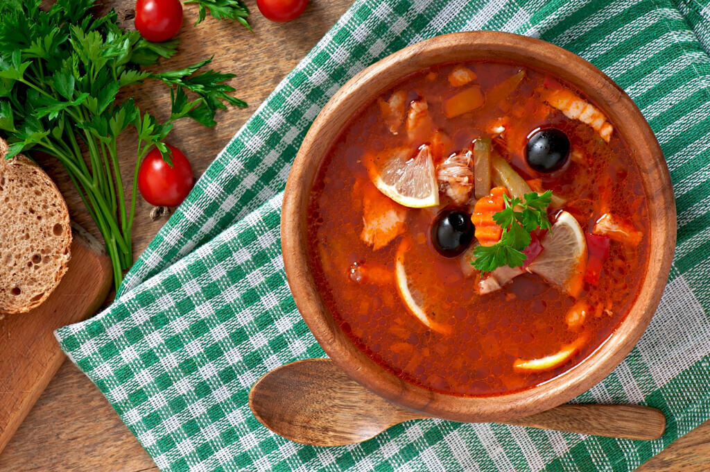   Soup solyanka Russian with meat, olives and gherkins in wooden bowl Журналист