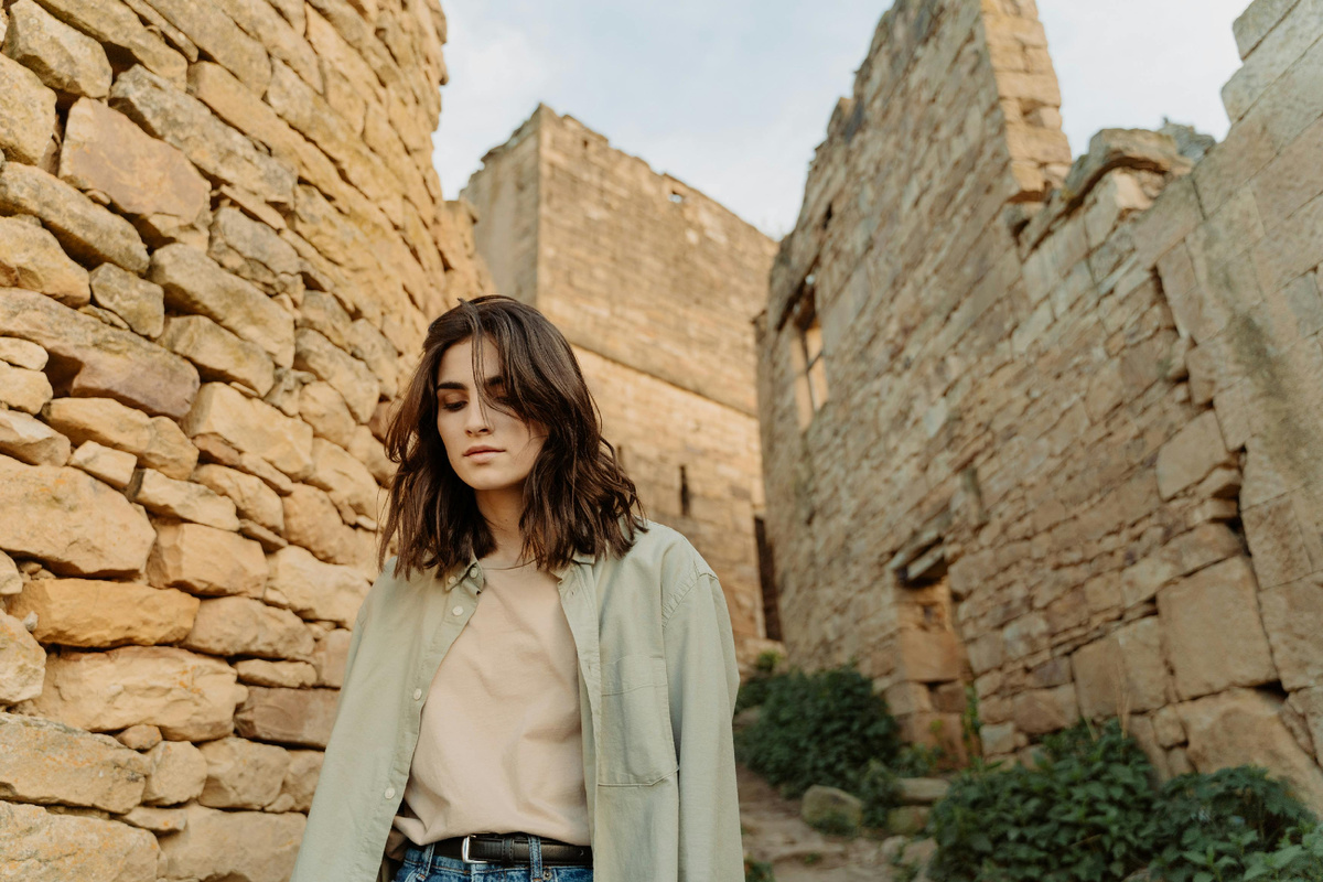 Молодая женщина идёт по старинным каменным улицам, осмысливая сорвавшееся путешествие и находя в этом спокойствие.