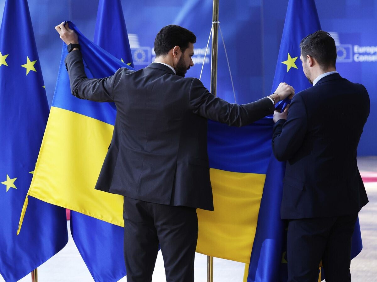    Сотрудники службы протокола вывешивают флаг Украины перед приездом Владимира Зеленского в Брюссель© AP Photo / Omar Havana