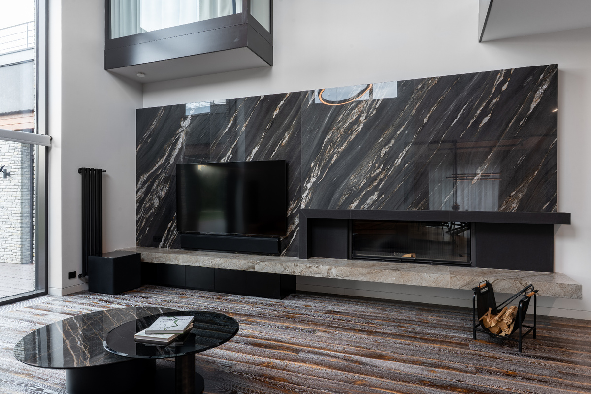 Керамогранит Tropical Black, имитирующий мрамор, украшает обширную стену гостиной