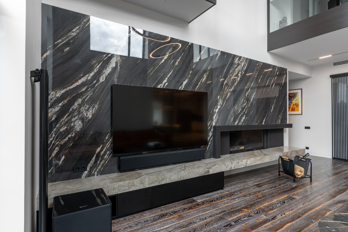 Керамогранит Tropical Black, имитирующий мрамор, украшает обширную стену гостиной