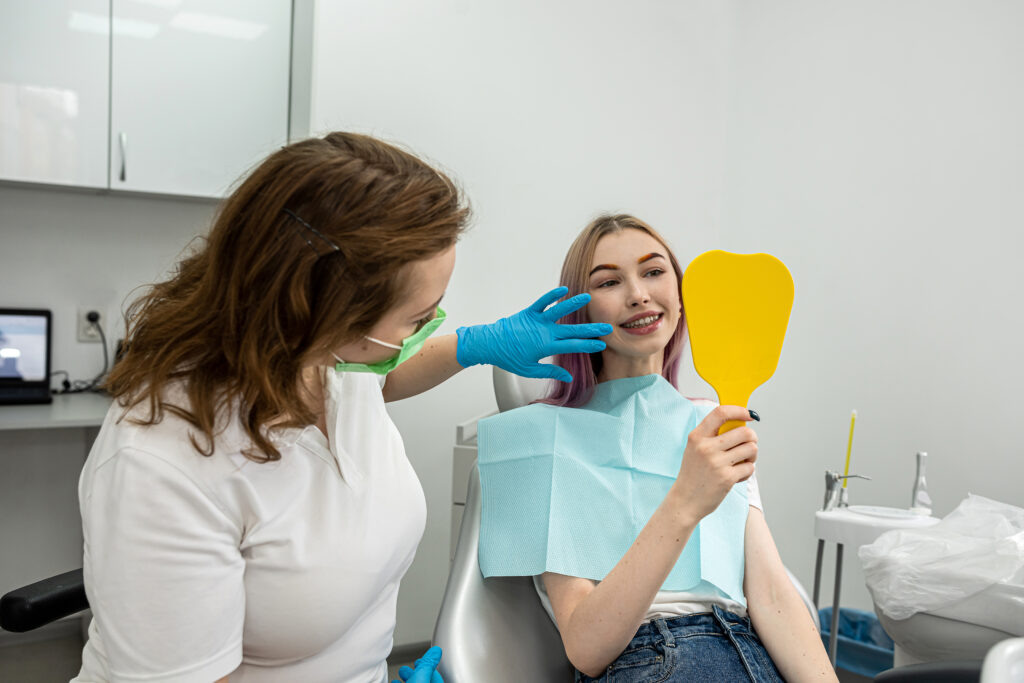    happy female patient is enjoying her beautiful toothy smile looking in the mirror in the dental office held by the dentist. health concept. teeth smile. Стоматология Во Владимире