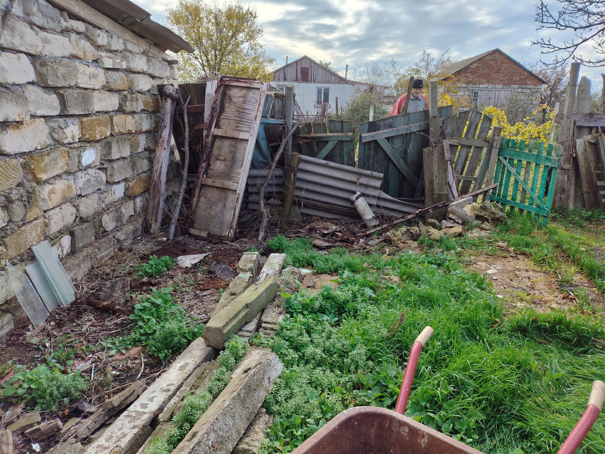 Олег уносит старые двери и щиты дальше к забору, а вот тут будет сарай.
