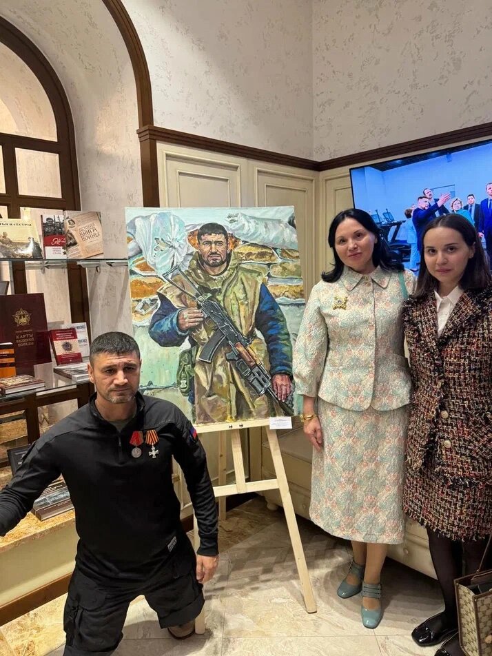  Рафи Джабар рядом со своим портретом, где он изображен еще до ранения. По другую сторону - Лилия Михайлова, руководитель попечительского совета БФ 