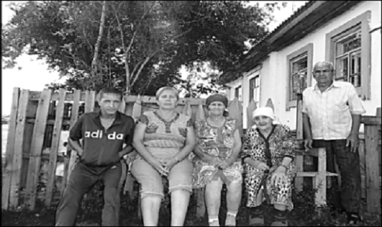 Карпухины Алексей, Мария со свахой, снохой и внуком около своего дома.