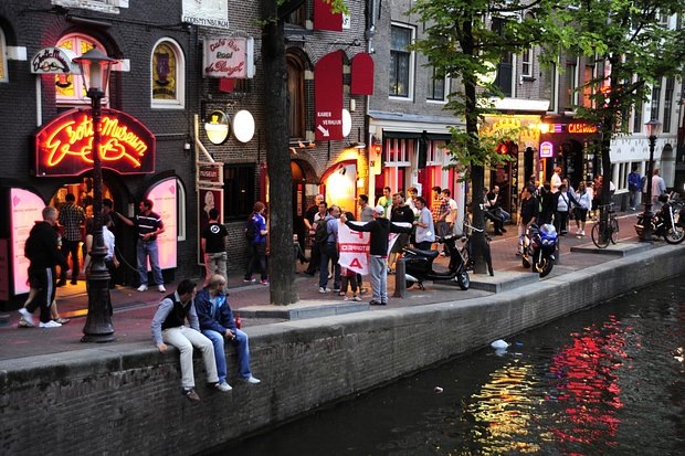    Туристы в квартале Де Валлен — визитной карточке Амстердама. Квартал также называют улицей красных фонарей, поскольку секс-работницы рекламируют свои услуги обнаженными прямо в витринах, которые освещены красным светом. Фото: Michael Zegers / Globallookpress.com
