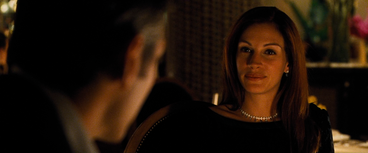 Дэни Оушен беседует с Тэсс в ресторане казино. В кадре преобладают тёплые тона. / 11 друзей Оушена, реж. Стивен Содерберг.