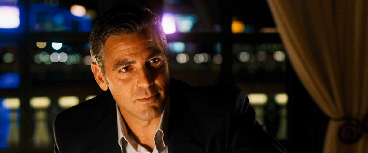 Дэни Оушен беседует с Тэсс в ресторане казино. В кадре преобладают тёплые тона. Силуэт Оушена освещает контровой свет. / 11 друзей Оушена, реж. Стивен Содерберг.