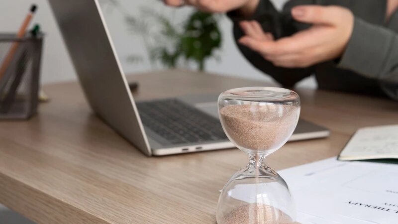     Женщина работает за ноутбуком, рядом стоят песочные часы. Фото: ru.freepik.com, автор freepik.