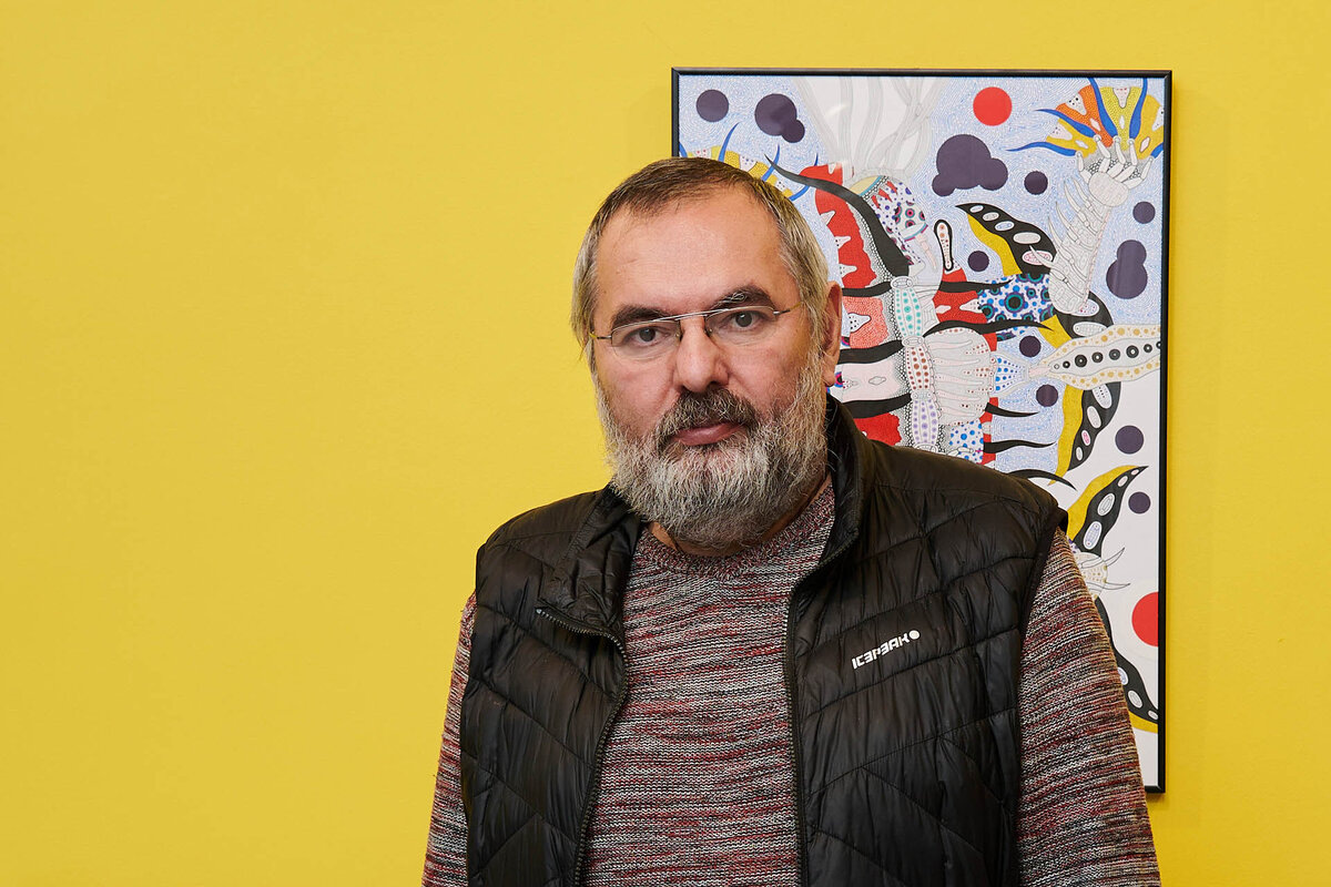 Художник Михаил Молочников на фоне своих картин