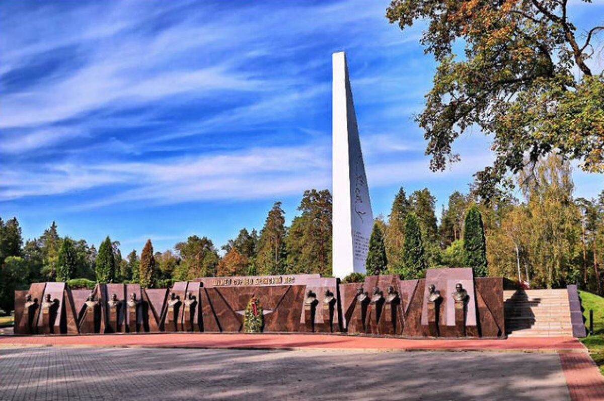 Курган Бессмертия в Брянске — мемориальный комплекс с высокой стелой и скульптурами партизан на фоне деревьев и синего неба