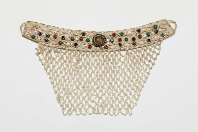 Ожерелье. Русские, сер. XIX в.

Ожерелье - шейно-нагрудное украшение в виде неширокой полосы из льняного холста, обшитого хлопчатобумажной тканью белого цвета, с пришитой к нижнему краю поднизи из рубленого перламутра в виде косой сетки, сужающейся книзу в два раза