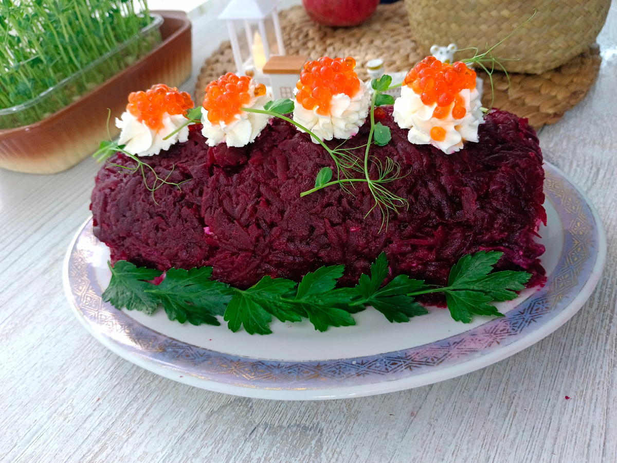 Ингредиенты                                                                Вареная свекла2 шт.                                              Картошка 3 шт.                                                                Яйца 3 шт.                                                                 Репчатый лук 80 г.                                                       Сельдь 1шт.                                                                      Соль по вкусу                                                                майонез 3 ст. л.т.                                                     Сушеный укроп 1 щепотка                                            Шаг 1.  Отварите свеклу и картошку в мундире. Положите ее в кастрюлю, залейте водой и включите огонь. Когда вода закипит, варите 30 минут на умеренном огне.                                                                Шаг 2Отправьте куриные яйца CO в кастрюлю. Залейте водой и поставьте на огонь. После закипания варите 10 минут.    Шаг 3Очистите репчатый лук и промойте его водой.Шаг 4Готовые яйца очистите от скорлупы.Шаг 5Очистите картошку и вареную свеклу.Шаг 6Измельчите лук.Шаг 7Постелите на разделочную доску пищевую пленку. Натрите свеклу на мелкой терке. Равномерно распределите ее по поверхности доски.Шаг 8Натрите картофель, чтобы его размер соответствовал свекле. Выложите поверх нее. Смажьте слой картофеля одной-двумя столовыми ложками майонеза.Шаг 9Посыпьте мелко нарезанным репчатым луком и слегка подсолите.Шаг 10Куриные яйца натрите на терке и выложите поверх слоя лука.Шаг 11Подготовьте селедку.Шаг 12На середину будущего рулета выложите кусочки сельди. Посыпьте их щепоткой сушеного укропа.  Шаг 13Начните аккуратно сворачивать рулет. Сначала одну сторону, затем другую.Шаг 14Он получится таким, как на фото.Шаг 15Закрутите края пищевой пленки. Уберите в холодильник на 3 часа.Шаг 16Аккуратно снимите пищевую пленку и украсьте творожным сыром и красной икрой.Нарежьте салат на порции и подавайте. Приятного аппетита!