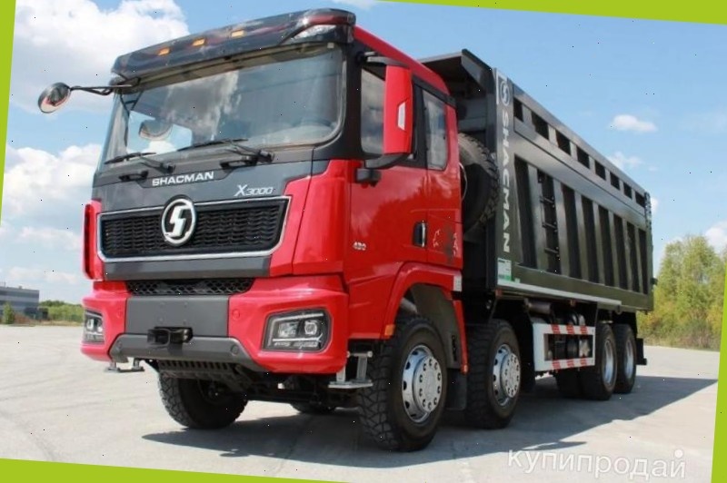 Четырехосный самосвал Шакман X3000 8x4 с красной кабиной и пустым кузовом на площадке официального дилера. Лучшая цена, чтобы купить.