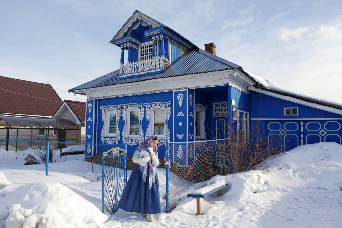 Русская девушка в павловопосадской шали на фоне деревянного дома с резными окнами. Нижегородская область, Россия. Источник фото: shutterstock.com