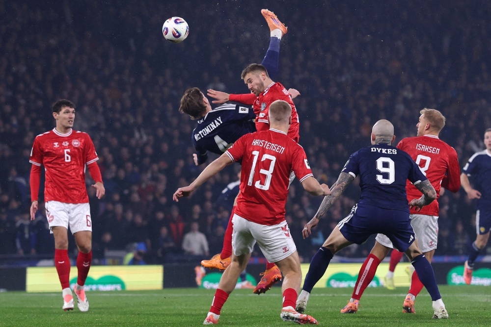    Тон матчу за прямую путевку на ЧМ-2026, в котором Шотландия дома обыграла Данию (4:2), задал точный удар через себя одного из лидеров хозяев Скотта Мактоминея (в темном). / REUTERS