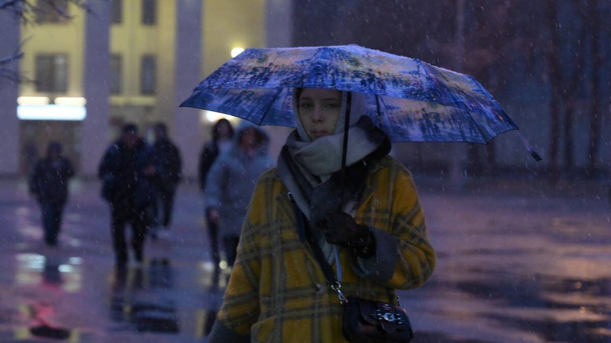    Студентка Анна Дмитриева прячется от осеннего дождя под зонтом / Фото: Пелагия Замятина / Вечерняя Москва