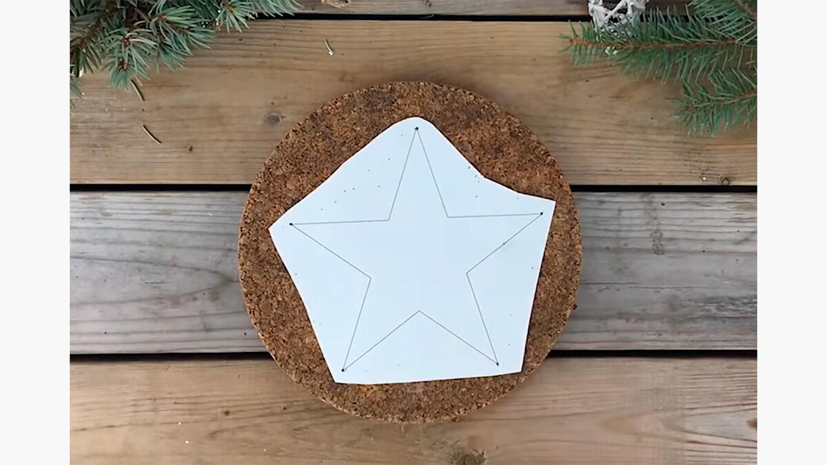    Шаг 1. Нарисуйте на листке бумаги звезду. Положите листок на дощечку из пробкового дерева или плотный картон — это основа для создания игрушкиEy to Zee Creative / YouTube