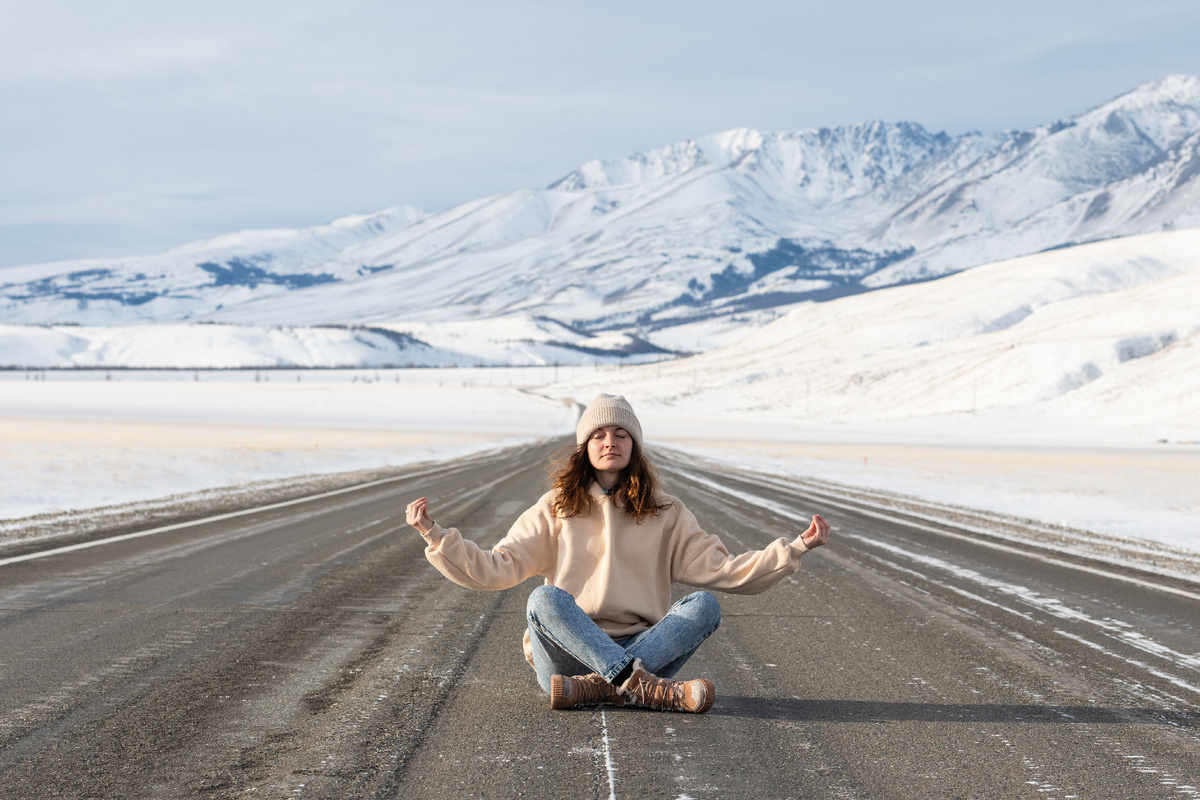 Молодая девушка медитирует на фоне гор зимой. Источник фото: shutterstock.com