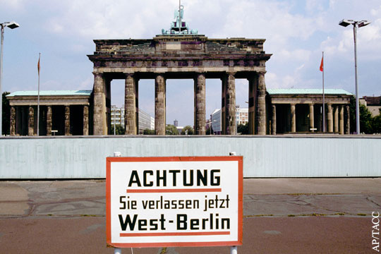 На фотографии на стенде у Берлинской стены надпись на немецком языке:
"Внимание! Вы покидаете Западный Берлин."
