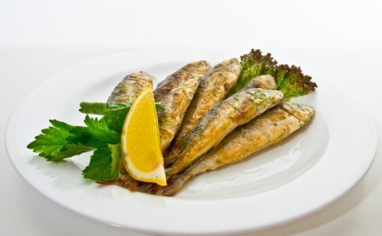 Блюдо из свежевыловленной ставриды, обжаренной до золотистой корочки. Подача на тарелке с лимоном и зеленью, фото foodpicasso.com