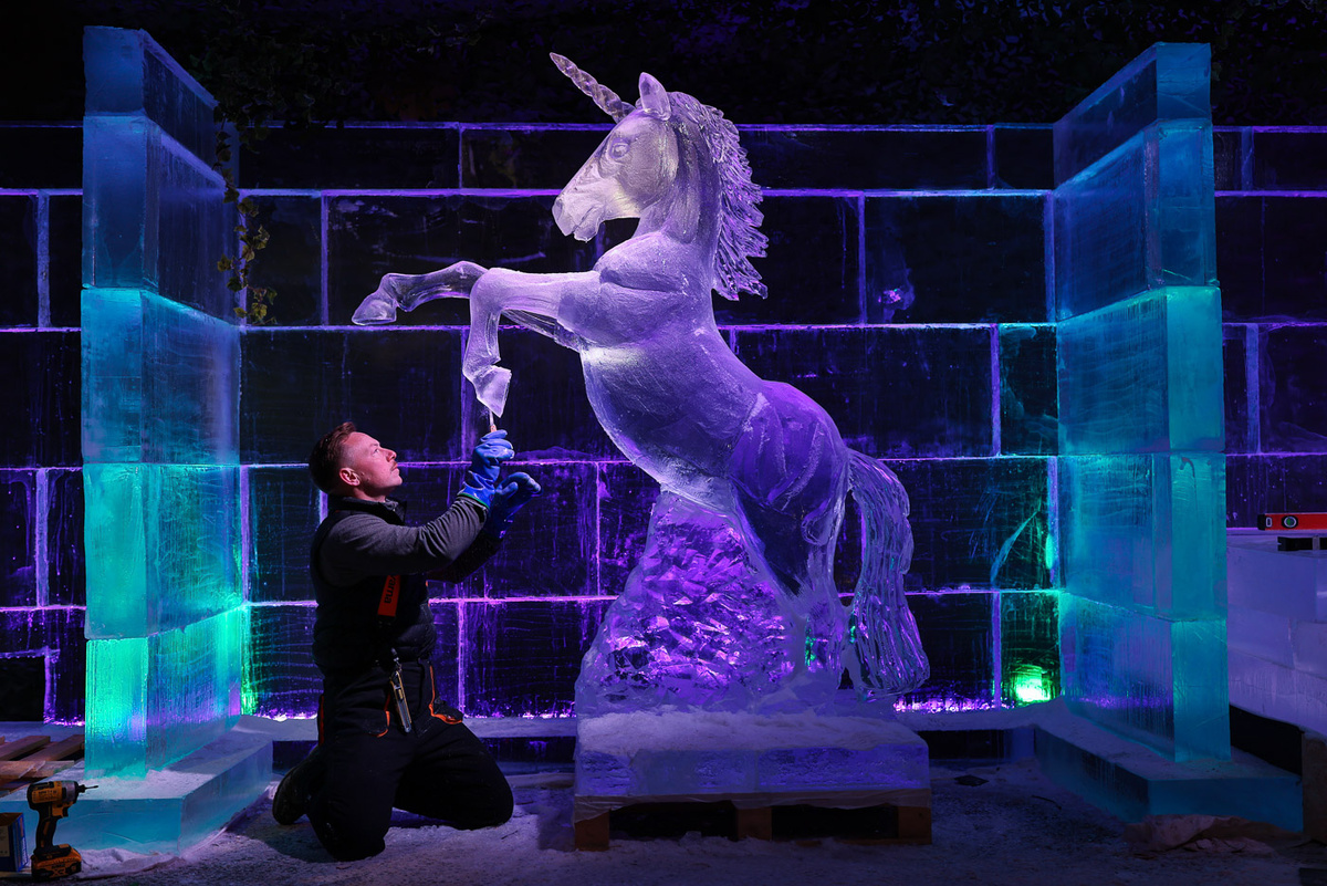   Jeff J Mitchell / Getty Images- Джек Хакни из Hamiltons Ice Sculptors наносит финальные штрихи на ледяную скульптуру единорога на рождественской ярмарке в Эдинбурге, Шотландия