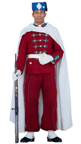 1. Небесно-голубая феска — головной убор гвардейцев пехотных батальонов. Кавалеристы носят аналогичную феску зеленого цвета. Ромб — традиционный марокканский символ, часто встречающийся в архитектуре и искусстве.

2. Пуговицы и бляха ремня украшены пятиконечной звездой-пентаграммой. Этот символ отсылает к легендарной печати Сулеймана, важной в исламской культуре. Изображение звезды есть в центре национального флага Марокко и на штандарте королевской гвардии.

3. Красный мундир — традиционный цвет марокканского государства с XII века и династии Алауитов, пришедших к власти в XVII веке.

4. Белый плащ. Белые знамена с цитатами из Корана использовались марокканцами в сражениях с IX по XVII века.

5. Винтовка «Маузер» 1893 года изготовлена в Испании. Она покрыта перламутром и украшена национальным орнаментом.