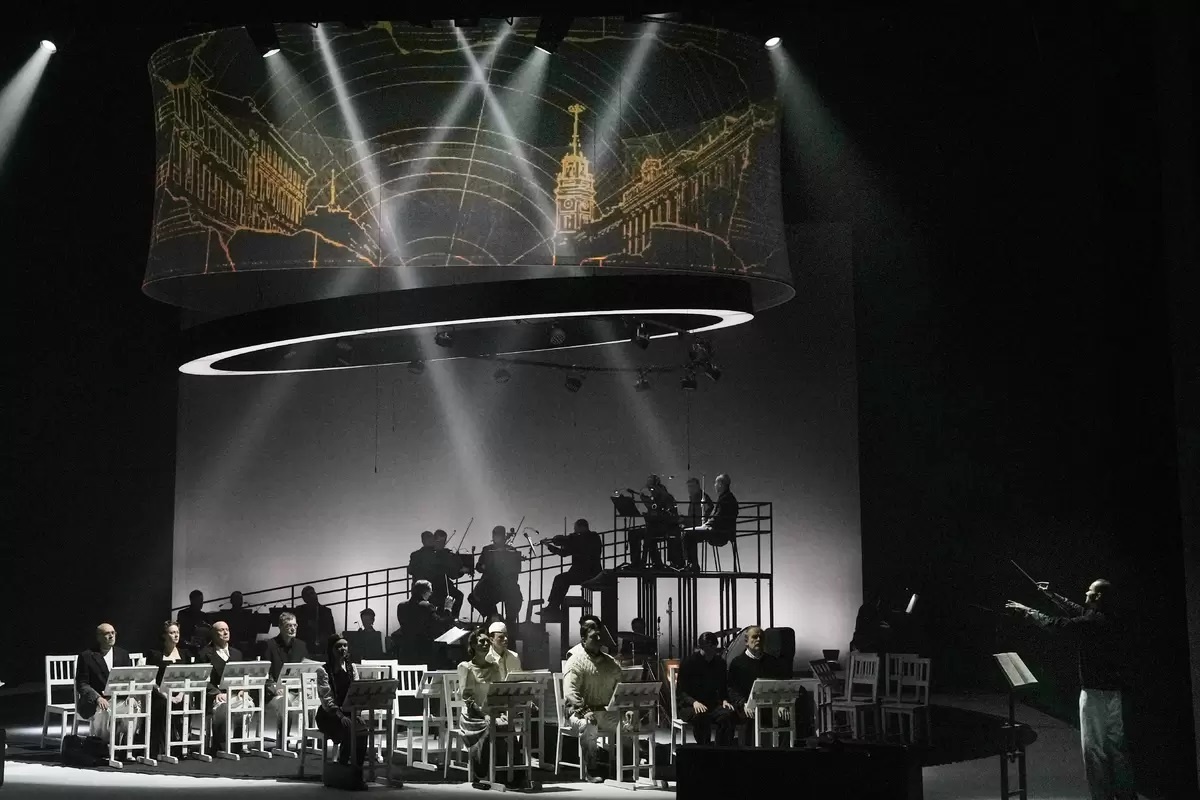 На первом плане актеры, на конструкции, словно знаки на нотном стане, музыканты. 