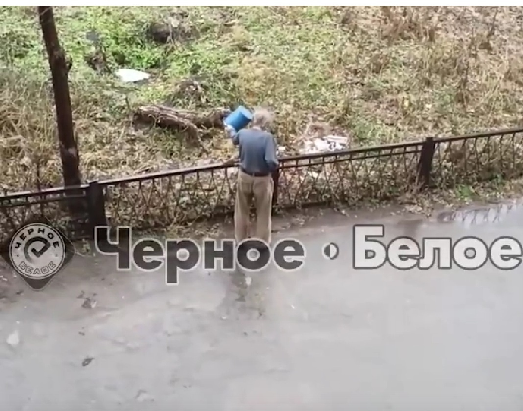 Жительница дома выливает отходы из ведра во дворе
