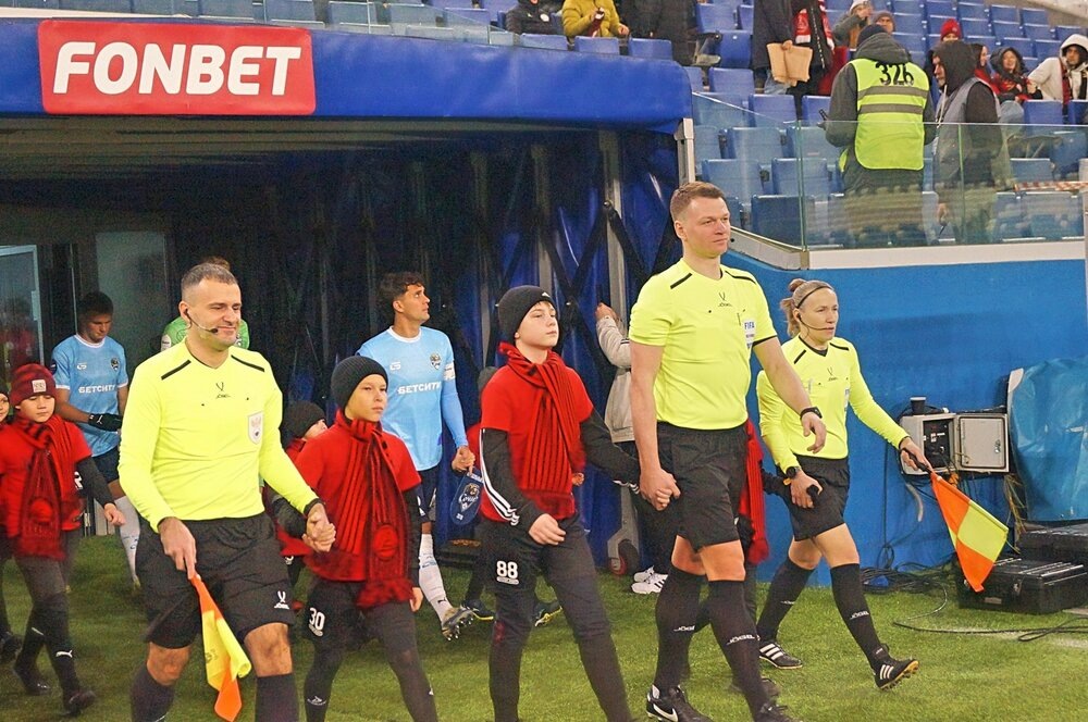 Бригада судей и стартовые составы команд судей выходят на поле в сопровождении детей.