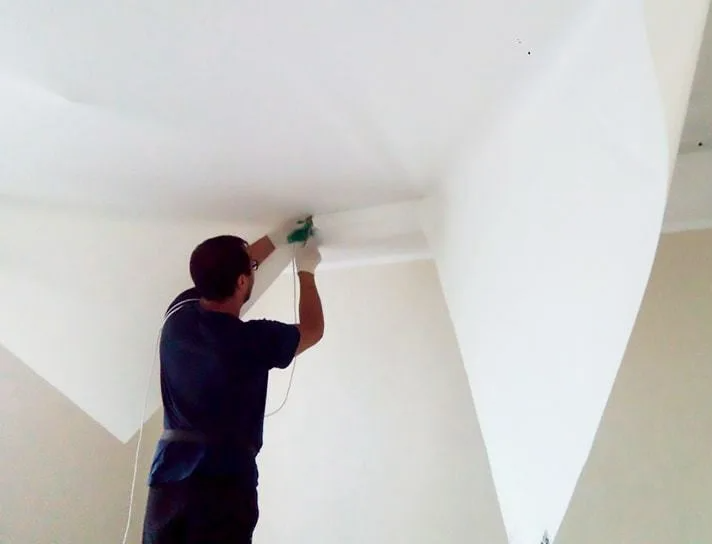 Мужчина устанавливет натяжной потолок. Источник изображения: https://dom-potolok.ru/