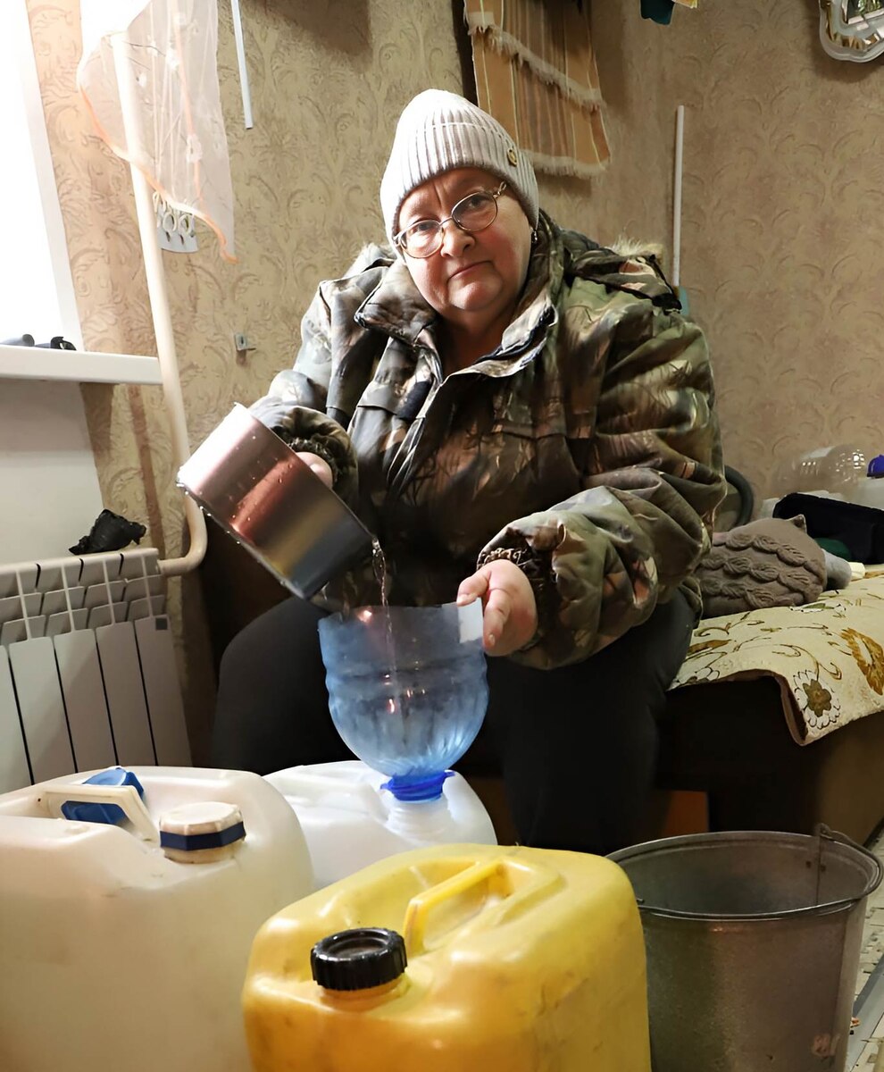 Галина СКАЧКОВА разливает воду по емкостям. «Наклоняю, отливаю в ведра, ставлю воронку, переливаю, – рассказывает Галина Ивановна. – Спина у меня больная. В «водный» день после всех манипуляций с водой доползаю до кровати и отлеживаюсь». Фото Алекандра ВАСИЛЬЕВА.