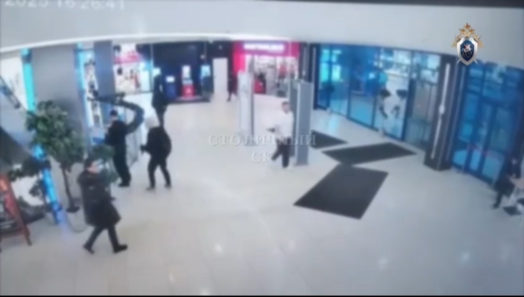 Скриншот из видео. Он сзади подходит в светлом капюшоне.