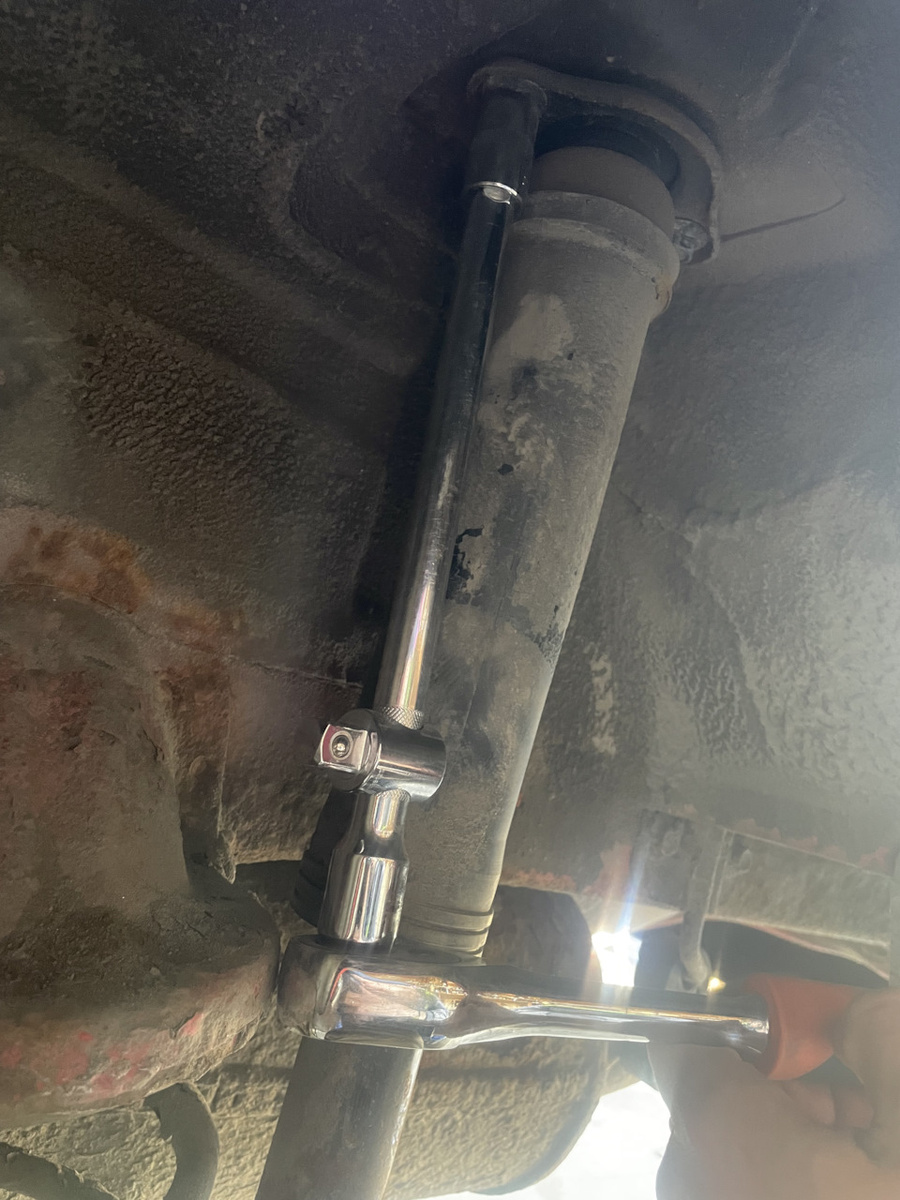 Трещеткой с удлинителем откручиваем два болта сверху