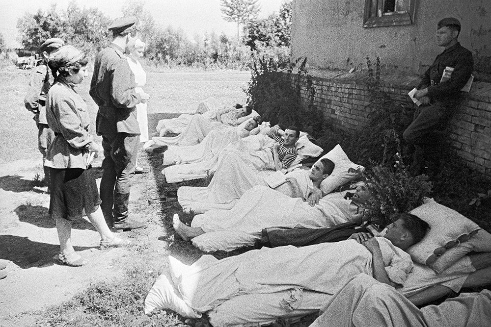    Великая Отечественная война 1941-1945 гг. Орловско-Курское направление. Константин Симонов читает свои стихи раненым бойцам, лежащим в тени дома на земле. / Фото: Яков Халип / РИА Новости