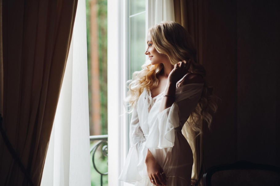 Задумчивая женщина смотрит в окно. Эта картинка отлично передает настроение размышлений и легкой грусти