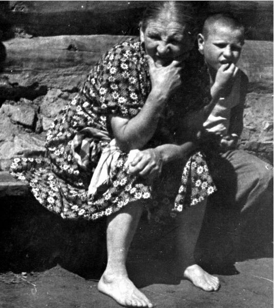 В окне, на фотографии, моя прабабушка. Прожила больше ста лет и за эти годы, как в молодости вышла замуж в эту деревню, так за всю жизнь ни разу из нее никуда не выезжала, нигде больше не была. Под окном, прядет пряжу, моя бабушка, мать моего отца. Рядом с ней, слева, тоже моя бабушка, мать моей мамы. 

