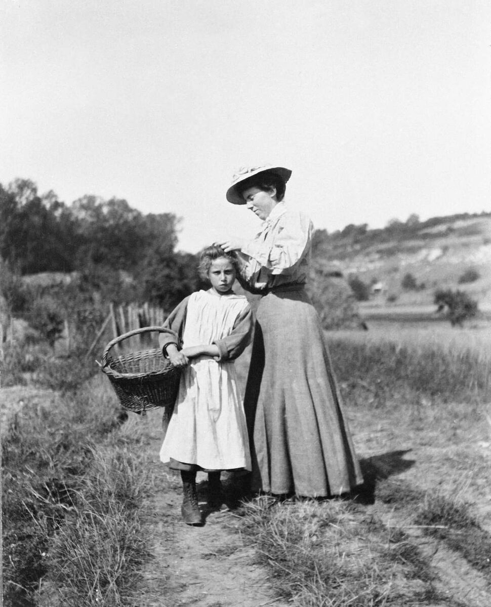 Фотография Хелен Макниколл, поправляющей прическу модели, Нью-Йорк, фотограф, вероятно, Доротея Шарп; на обороте этой фотографии написано: "Так жарко, что я обмотала шею платком. В тени около 90 градусов тепла".