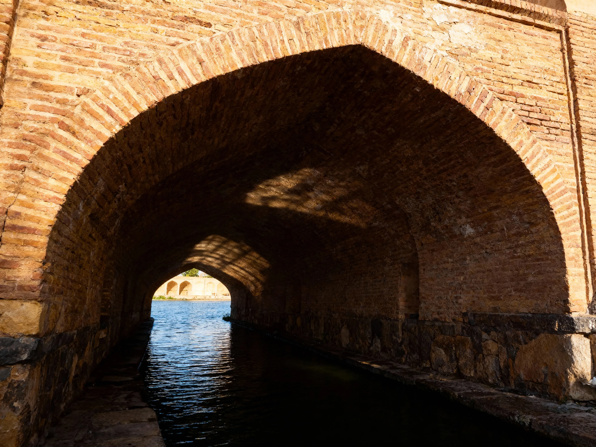 Вот он, главный секрет персидских зодчих: чтобы спастись от палящего зноя, они строили не дворцы, а многофункциональные мосты. Эти мощные арки скрывают не просто реку, а прохладную гостиную для разговоров, где даже шёпот путешествует по воде.