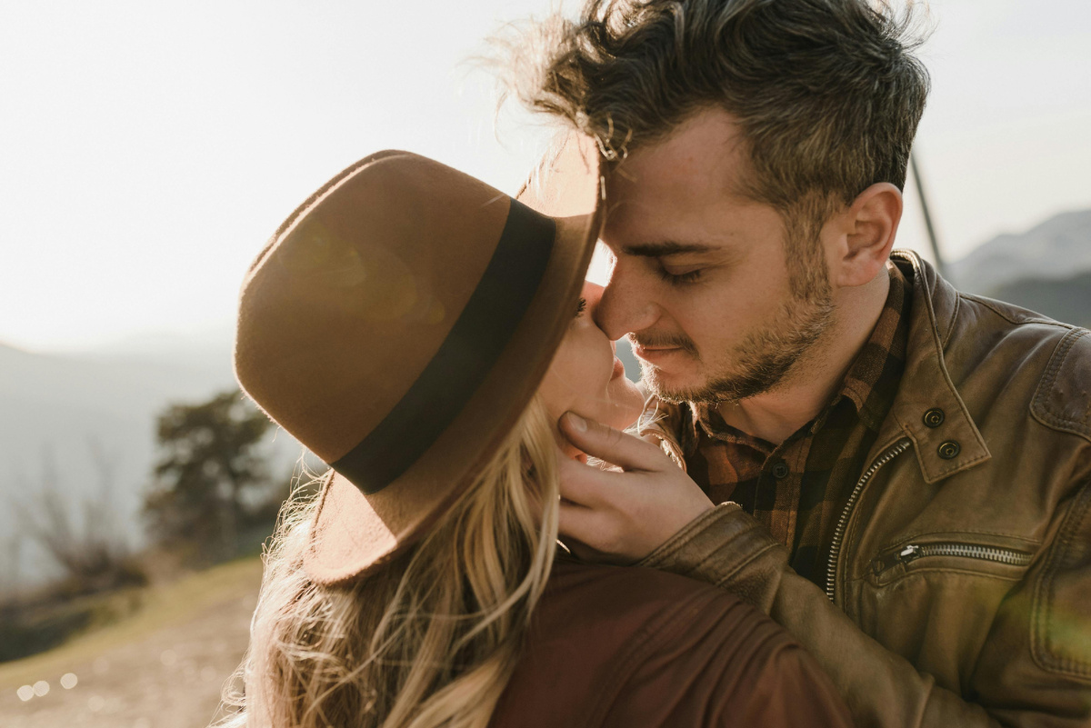 Пара нежно обнимается и целуется на природе — момент близости, который подчёркивает важность благодарности и тёплого отношения друг к другу.