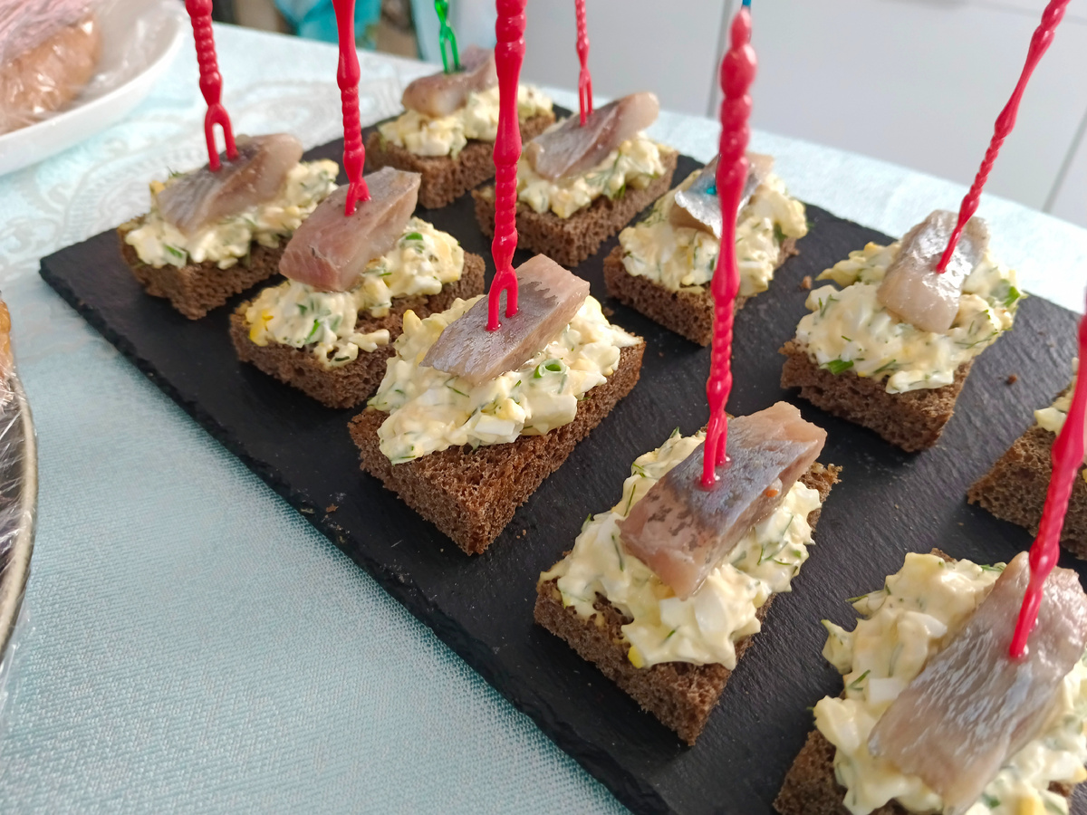 ▌ Рецепт закуски с селёдкой на чёрном хлебе с яйцами. Эта простая и вкусная закуска идеально подойдёт для любого праздника или семейного ужина.                                                                                      ▌ Ингредиенты:                                                               Филе сельди — 200 г.                                                 Чёрный хлеб.                                                             Куриные яйца — 4 шт.                                              Зелёный лук — 3 веточки                                       Майонез — 3 столовые ложки.                              Твёрдый сыр — 100 г (по желанию).                            Растительное масло — 1 столовая ложка                                           Свежемолотый перец — по вкусу                            Укроп.                                                                         Процесс приготовления:                                                     1. Подготовка яиц и сыра   Отварите яйца вкрутую, очистите и натрите на средней терке. Если используете твёрдый сыр, натрите его отдельно.       2. Приготовление начинки   Мелко нарежьте зелень и смешайте  с натертыми яйцами. Добавьте майонез, соль и свежемолотый перец по вкусу. Хорошо перемешайте.                        3. Обжаривание хлеба   Нарежьте чёрный хлеб порционными ломтиками и обжарьте с одной стороны до золотистой корочки на сковороде с небольшим количеством растительного масла.4. Сборка бутербродов   На обжаренный хлеб выложите слой яичной массы. Поверх неё положите кусочки филе сельди.                                                           ▌ Советы по подаче:- Чтобы бутерброды выглядели ещё привлекательнее, можно посыпать их свежими листьями зелени перед подачей.- Используйте качественные продукты, особенно сельдь, чтобы подчеркнуть натуральный вкус блюда.Получившиеся бутерброды станут отличным дополнением к любому столу и порадуют гостей своей простотой и вкусом. Приятного аппетита!