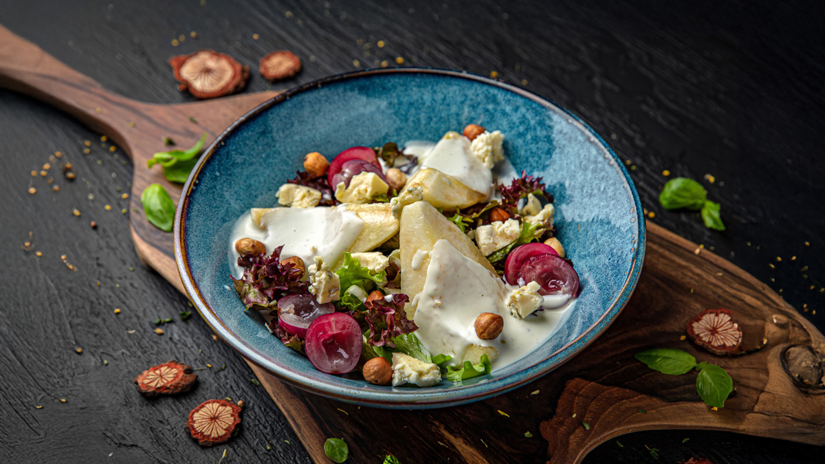 Салат с Дор Блю, грушей и бри на сервировочной тарелке.